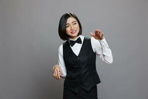 Catering service cheerful smiling asian woman employee dancing. Carefree joyful young waitress wearing uniform making moves with hands while posing in studio on gray background photo