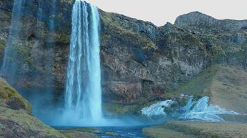 majestuoso seljalandsfoss cascada hacia marzo 2023, hermosa agua fluido abajo apagado de colina. escandinavo cascada en nórdico islandés paisaje con acantilados y montañas. Mano disparo. foto