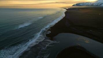 Aerial view of arctic black sand beach in iceland, beautiful ocean coastline with icelandic scenery. Spectacular atlantic shore with waves crashing on beaches, panoramic view. Slow motion. photo