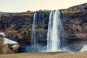 Majestic cascade in icelandic scenery with river falling off cliffs and mountains, seljalandsfoss waterfall with stream. Outstanding nordic nature with spectacular massive water flow. photo