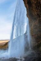 Inside arctic skgafoss waterfall with river stream frunning down off mountain edges, icelandic cascade with water flow falling. Scandinavian nature and wilderness, beautiful landscape. photo