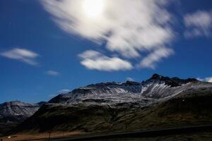 Scandinavian countryside caught in fantastic night photography displaying snowy chain of mountains next to valley in Iceland. Snow covered hillsides and rocky peaks in Icelandic scenery. photo