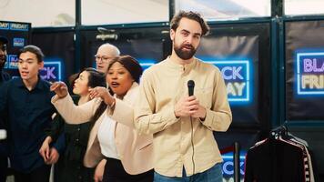 TV news reporter broadcast crazy scene with aggressive crowd of shoppers at local mall during black friday sales. Male journalist making live reportage about bargain hunting event. photo