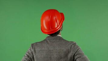 Rear view portrait of a contractor wearing hardhat looking at the green screen video