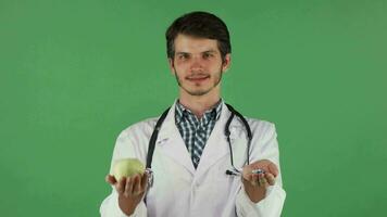 Young doctor holding green apple and bunch of pills video