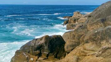 surfer golven turkoois blauw water rotsen kliffen keien puerto escondido. video