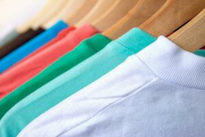 Fashion T-shirt on clothing rack - Closeup of bright colorful closet on wooden hangers in store closet. photo