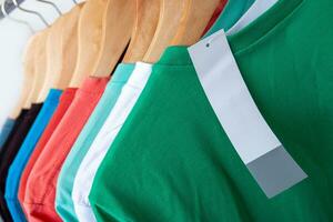 Fashion T-shirt on clothing rack - Closeup of bright colorful closet on wooden hangers in store closet. photo