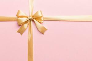 Top view of gold ribbon rolled and yellowbow isolated on colored background. Flat lay with copy space photo