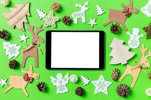 Christmas green background with holiday toys and decorations. Top view of digital tablet. Happy New Year concept photo