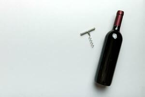 One Bottle of red wine with corkscrew on colored table. Flat lay, top view wth copy space photo