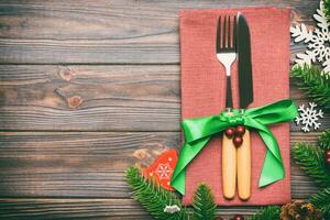 Top view of christmas decorations on wooden background. Fork and knife on napkin tied up with ribbon and empty space for your design. New year pattern concept photo