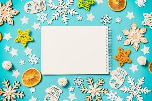 Top view of notebook on blue background with New Year toys and decorations. Christmas time concept photo