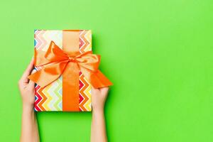 Top view of female hands holding christmas or other holiday handmade present box package in the palms, flat lay table background with copy space photo