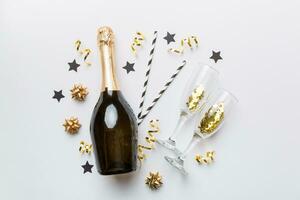 bottle of champagne with glasses and colorful confetti on colored background. top view flay lay photo