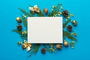 Flat lay Christmas composition. square Paper blank, pine tree branches, christmas decorations on Colored background. Top view, copy space for text photo