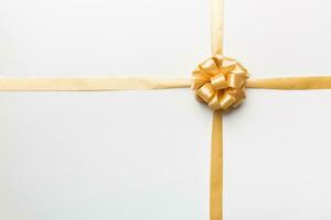 Top view of gold ribbon rolled and yellowbow isolated on colored background. Flat lay with copy space photo