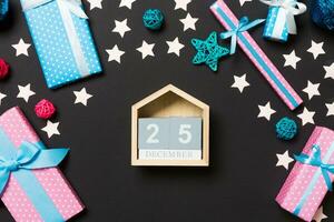 Top view of female hands holding calendar on black background. The twenty fifth of December. Holiday decorations. Christmas time concept photo