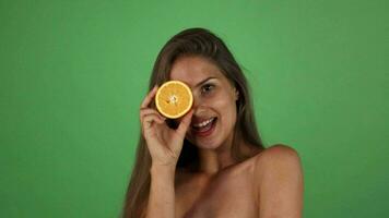 studio coup de une magnifique content femme souriant en portant moitié de un Orange video