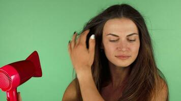 Young woman blow drying her hair on chromakey background video