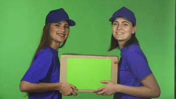 Two cheerful female delivery service workers smiling holding cardboard box video