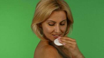 Stunning mature woman smiling to the camera while using cotton pad on her skin video