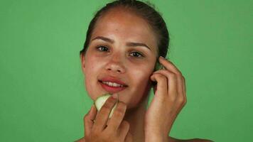 maravilloso mujer masajear su cara con rebanadas de Pepino video