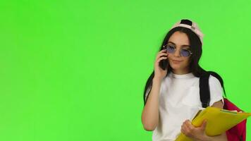 Cheerful female student talking on the phone, holding her books video