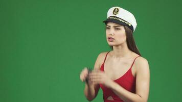 sbalorditivo donna nel un' marinaio berretto sorridente dopo guardare lontano attraverso binocolo video