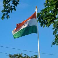 India flag flying high at Connaught Place with pride in blue sky, India flag fluttering, Indian Flag on Independence Day and Republic Day of India, tilt up shot, Waving Indian flag, Har Ghar Tiranga photo