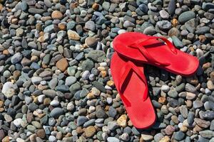 Red flip flops on a pebble beach. photo