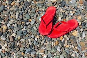 Red flip flops on a pebble beach photo