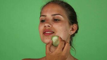 aantrekkelijk vrouw wrijven haar gezicht met een plak van komkommer video