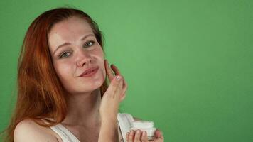 Attractive young red haired woman applying face cream video