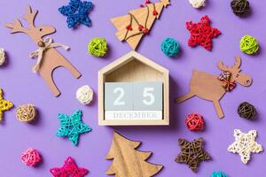 Top view of wooden calendar. The twenty fifth of December. New Year decorations on purple background. Festive stars and balls. Merry Christmas concept photo