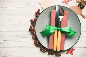 Top view of plate, fork and knife served on Christmas decorated wooden background. New Year Eve concept with copy space photo