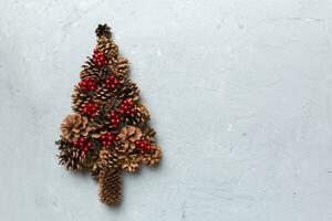 Christmas tree made from natural cones on colored background, view from above. New Year minimal concept with copy space photo