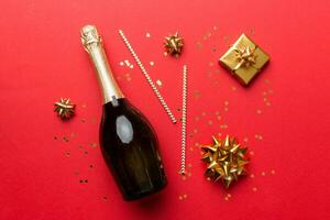 Bottle of champagne with colored glitter, confetti and gift box space for text on colorfull background, top view. Hilarious, christmas and birthday celebration photo