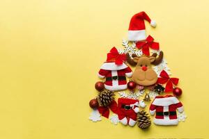 Christmas tree made from colored suit santa decoration on colored background, view from above. New Year minimal concept with copy space photo