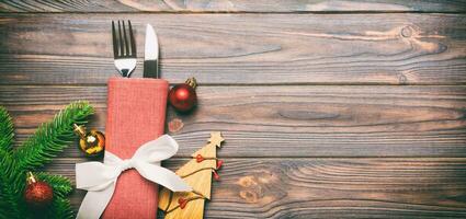 Top view Banner of fork and knife on napkin with christmas decorations and new year tree on wooden background. Holiday and festive concept with copy space photo