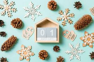 vista superior del calendario de madera, juguetes navideños y decoraciones sobre fondo azul de navidad. el primero de enero. concepto de tiempo de año nuevo foto