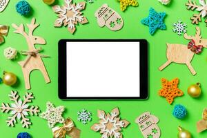 Top view of digital tablet on green background with New Year toys and decorations. Christmas time concept photo