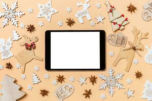 Festive decorations and toys on orange background. Top view of digital tablet. Merry Christmas concept photo