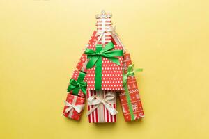 Christmas tree made of beautifuly wrapped presents on colored background, view from above. New Year gift box minimal concept with copy space photo