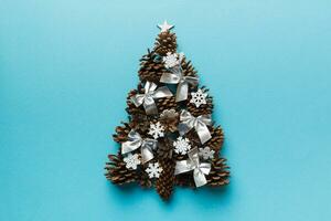 Christmas tree made from natural cones on colored background, view from above. New Year minimal concept with copy space photo