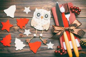 Top view of New Year dinner on wooden background. Festive cutlery on napkin with christmas decorations and toys. Close up of family holiday concept photo