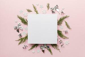 Flat lay Christmas composition. square Paper blank, pine tree branches, christmas decorations on Colored background. Top view, copy space for text photo