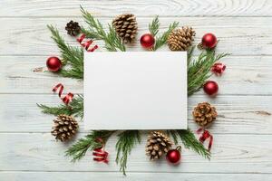 Flat lay Christmas composition. square Paper blank, pine tree branches, christmas decorations on Colored background. Top view, copy space for text photo