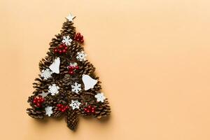 Christmas tree made from natural cones on colored background, view from above. New Year minimal concept with copy space photo