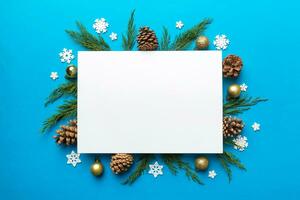 Flat lay Christmas composition. square Paper blank, pine tree branches, christmas decorations on Colored background. Top view, copy space for text photo